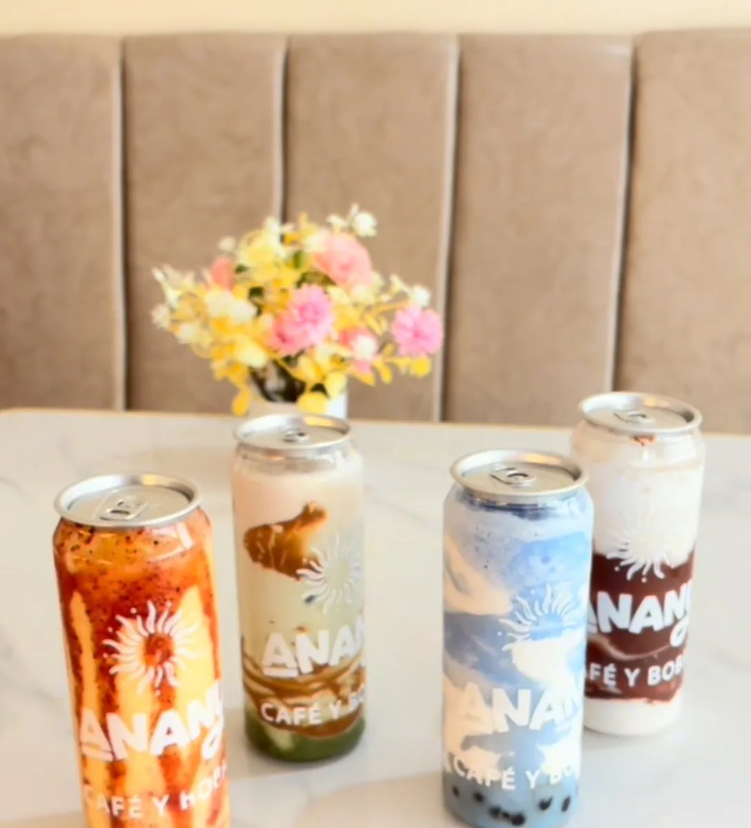 Cuatro latitas de Anany sobre una mesa de mármol con flores